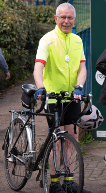 A man smiling stood next to his bike wearing the GO pendant alarm
