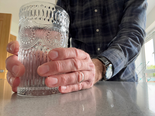 A picture of a man holding a glass of water with two hands